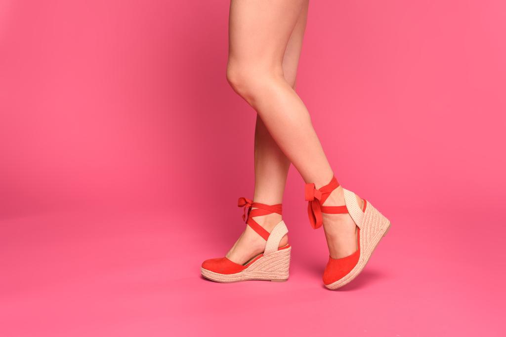 περικοπεί shot από όμορφα γυναικεία πόδια σε κόκκινο υποδήματα που απομονώνονται σε ροζ - Φωτογραφία, εικόνα
