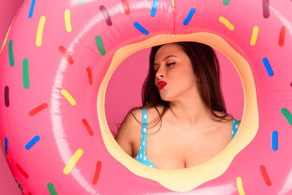 belle femme brune en maillot de bain soufflant baiser à travers anneau gonflable
 - Photo, image