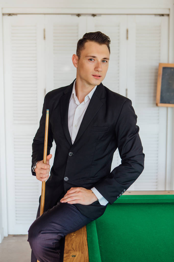 Молодий красивий чоловік, одягнений у класичний костюм, грає в більярд самостійно
 - Фото, зображення