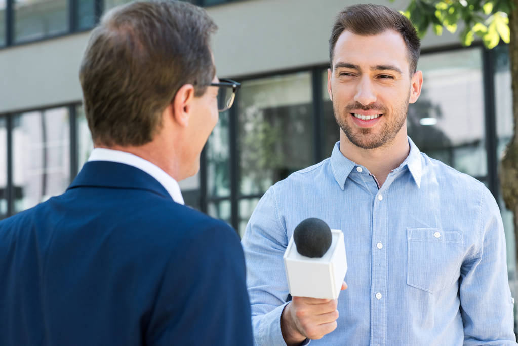 reporter di notizie professionale intervistando uomo d'affari di successo con microfono
 - Foto, immagini