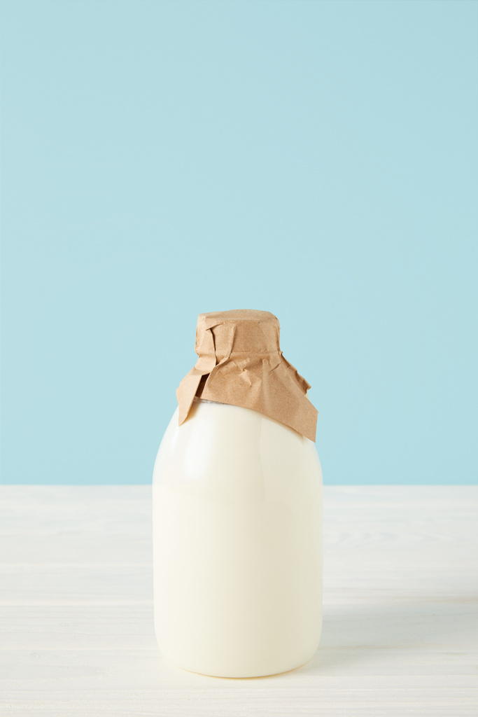 closeup görünümü tarafından mavi renkli kağıda sarılı şişe taze süt  - Fotoğraf, Görsel