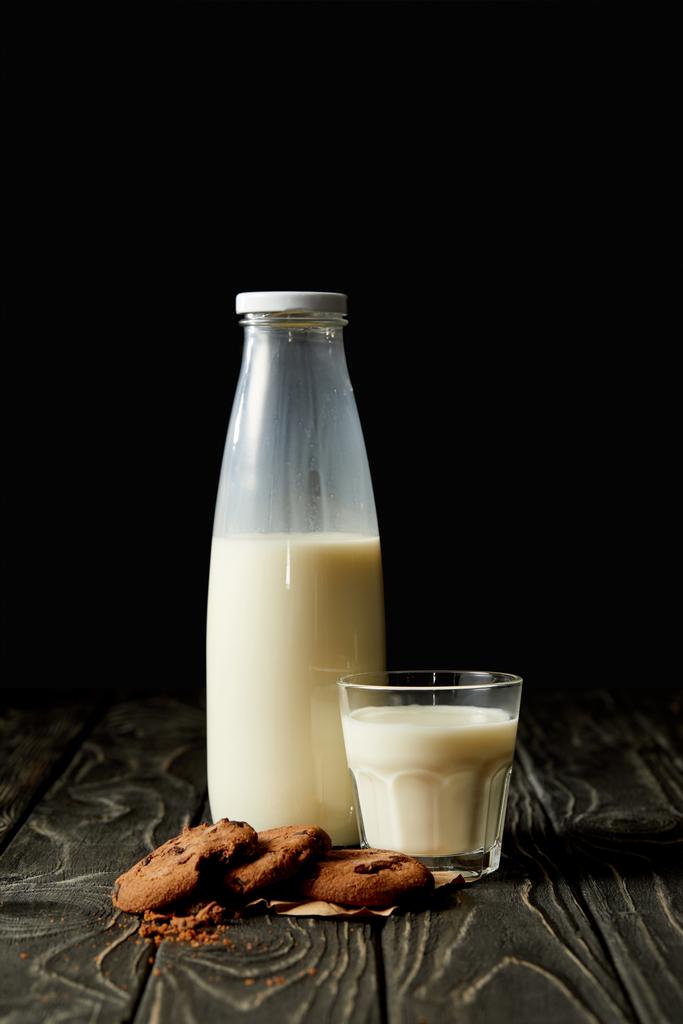 csokoládé cookie-kat, tej, üveg és üveg-fekete háttér  - Fotó, kép