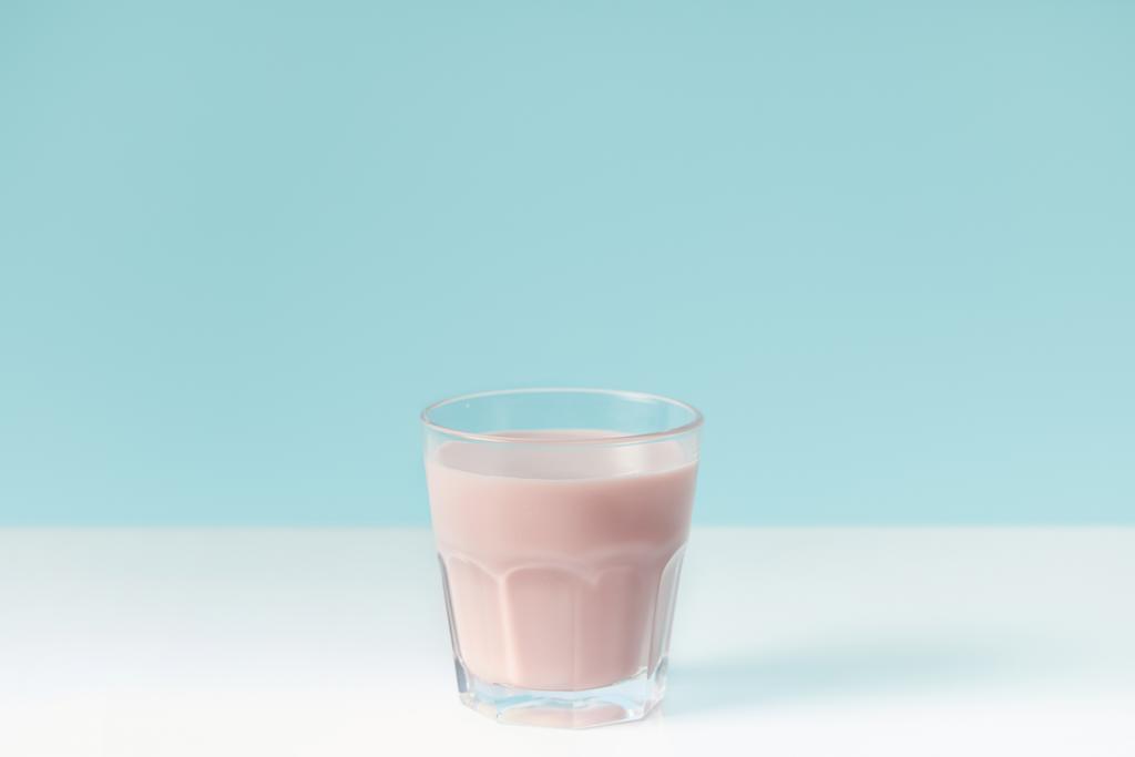 closeup view of strawberry milkshake in glass on blue background  - Photo, Image