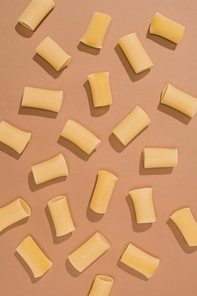 bovenaanzicht van pasta gemorst op beige oppervlak - Foto, afbeelding