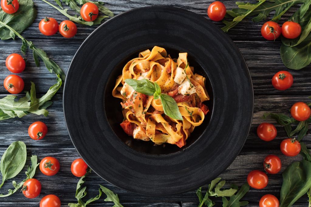 bovenaanzicht van heerlijke pasta op de plaat en verse groenten op houten tafel  - Foto, afbeelding