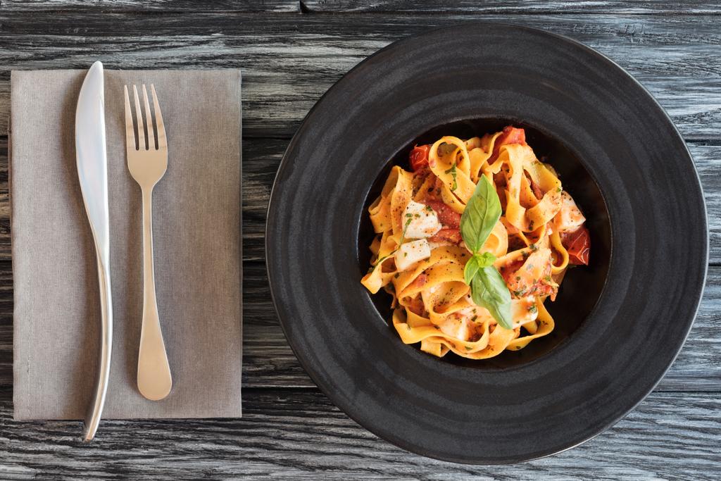 top view of delicious italian pasta and fork with knife on wooden table - Photo, Image