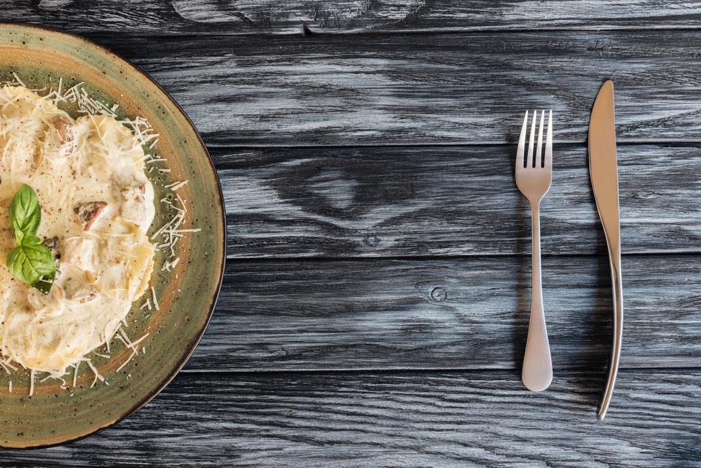 herkullinen ravioli pinaatin ja ricotta-juuston, haarukan ja veitsen kanssa puupöydällä
  - Valokuva, kuva