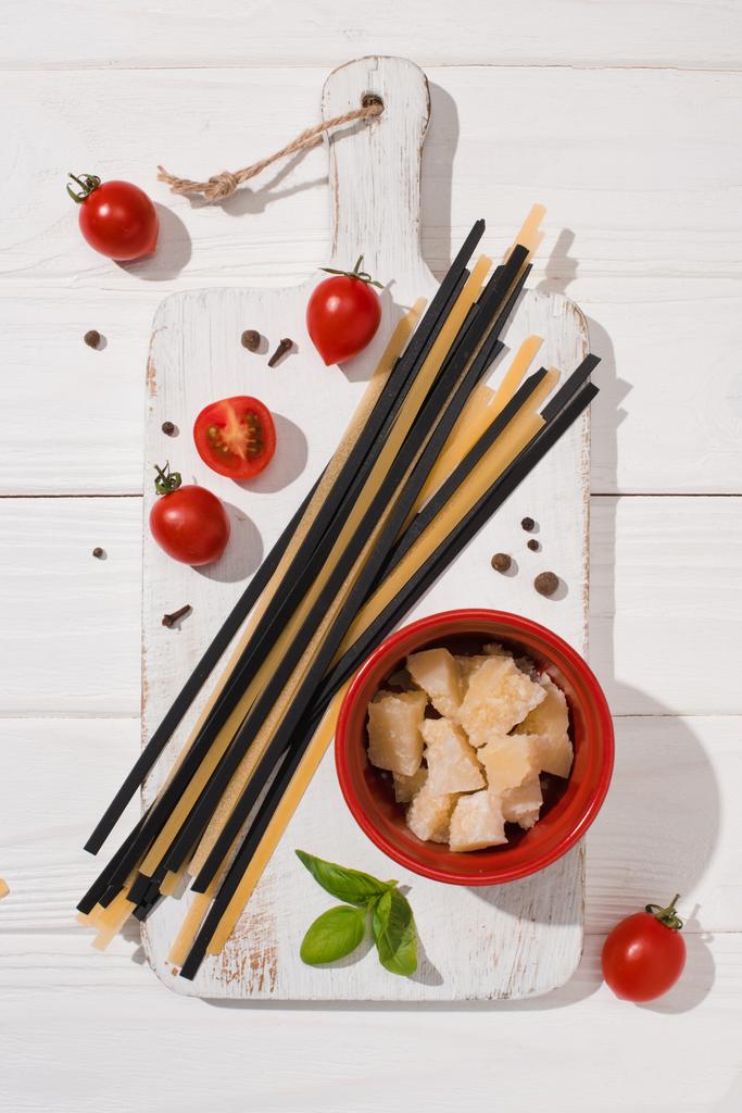 felülnézete különféle olasz ételeket, a fehér és a fekete spagetti fehér fa vágódeszka - Fotó, kép
