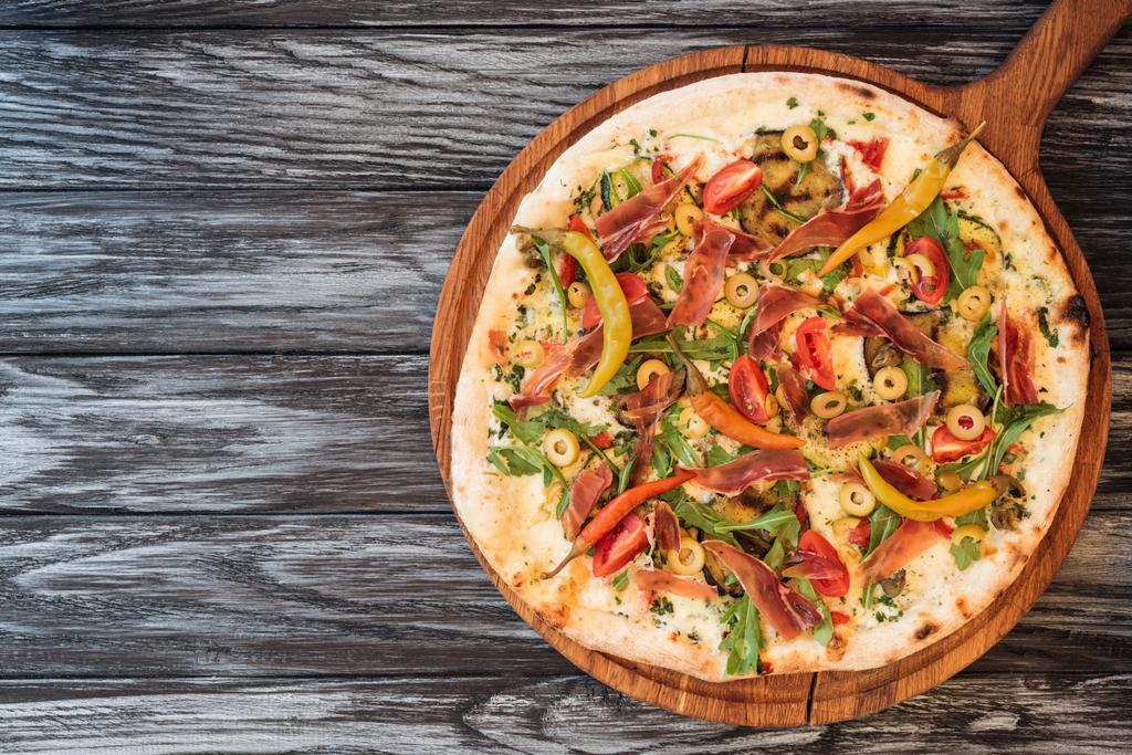 смачна піца з овочами, сиром і м'ясом на дерев'яному столі з копією простору
  - Фото, зображення