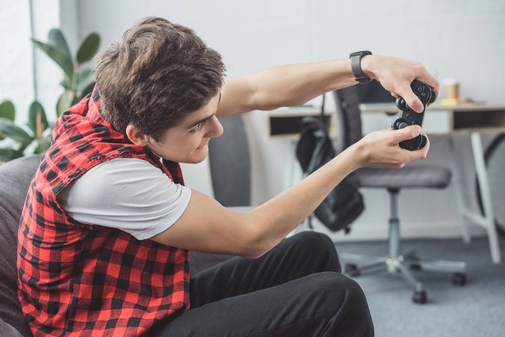 emocionado jugador adolescente jugando videojuego con joystick en casa
 - Foto, imagen
