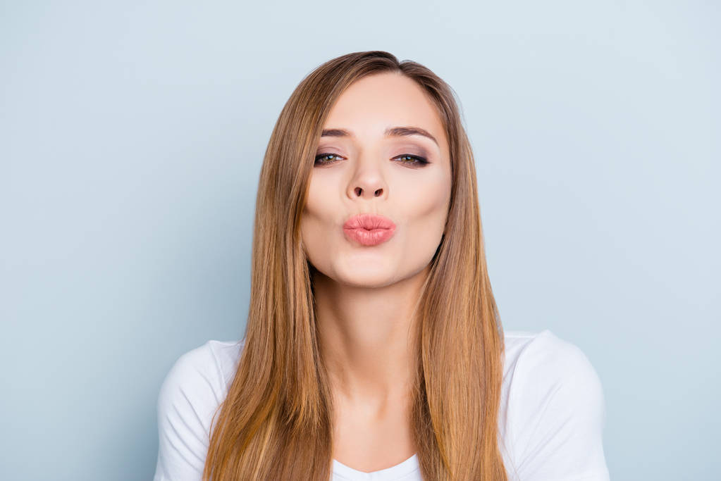 Retrato de hermosa chica de pelo castaño lindo enviando beso con labios de puchero aislado en fondo gris mirando a la cámara
 - Foto, Imagen