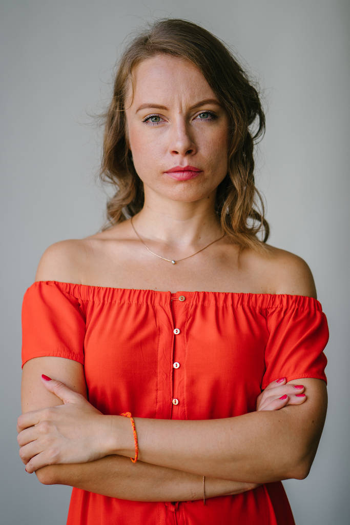 Retrato de una joven y atractiva mujer europea en un vestido de verano naranja posando. Ella es rubia con ojos verdes y sonríe con confianza
. - Foto, Imagen