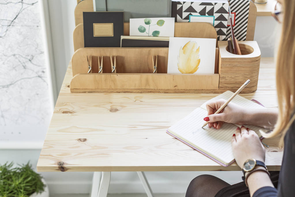 Крупный план девушки, пишущей дневник карандашом, сидящей за деревянным столом с организатором
 - Фото, изображение