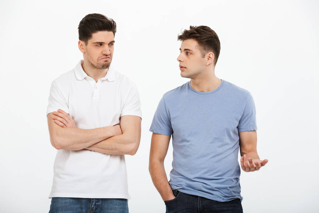Portrait of two upset young men arguing isolated over white background - Photo, Image
