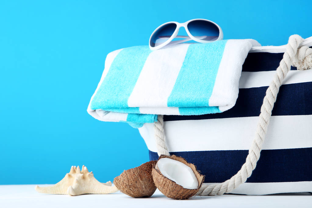 Bolsa de verano con toalla y cocos sobre fondo azul
 - Foto, imagen