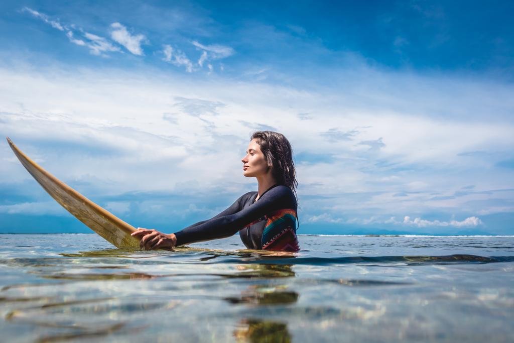 вид збоку молоді актриса в гідрокостюм на борту серфінгу в океані в Нуса Дуа Beach, Балі, Індонезія - Фото, зображення
