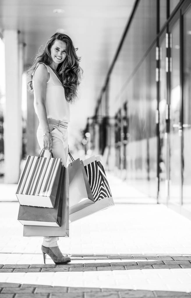 モールの路地に買い物袋を持つ幸せな若い女性の完全な長さの肖像画 - 写真・画像