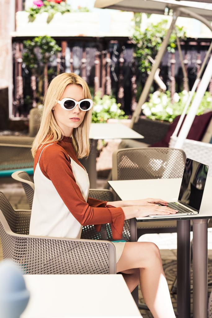 hermosa mujer joven en gafas de sol utilizando el ordenador portátil
 - Foto, Imagen