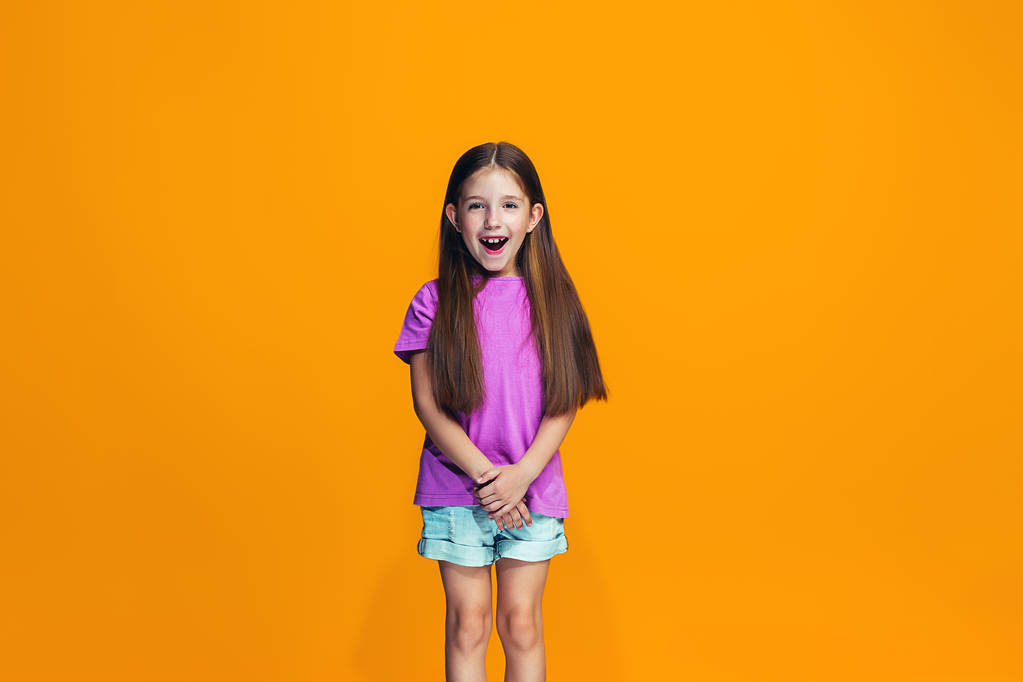 La chica adolescente feliz de pie y sonriendo contra el fondo naranja
. - Foto, Imagen