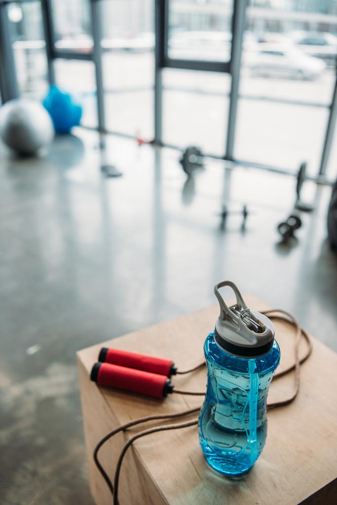 Προβολή closeup της άλμα σχοινί και μπουκάλι νερό σε ξύλινο κουτί στο γυμναστήριο - Φωτογραφία, εικόνα