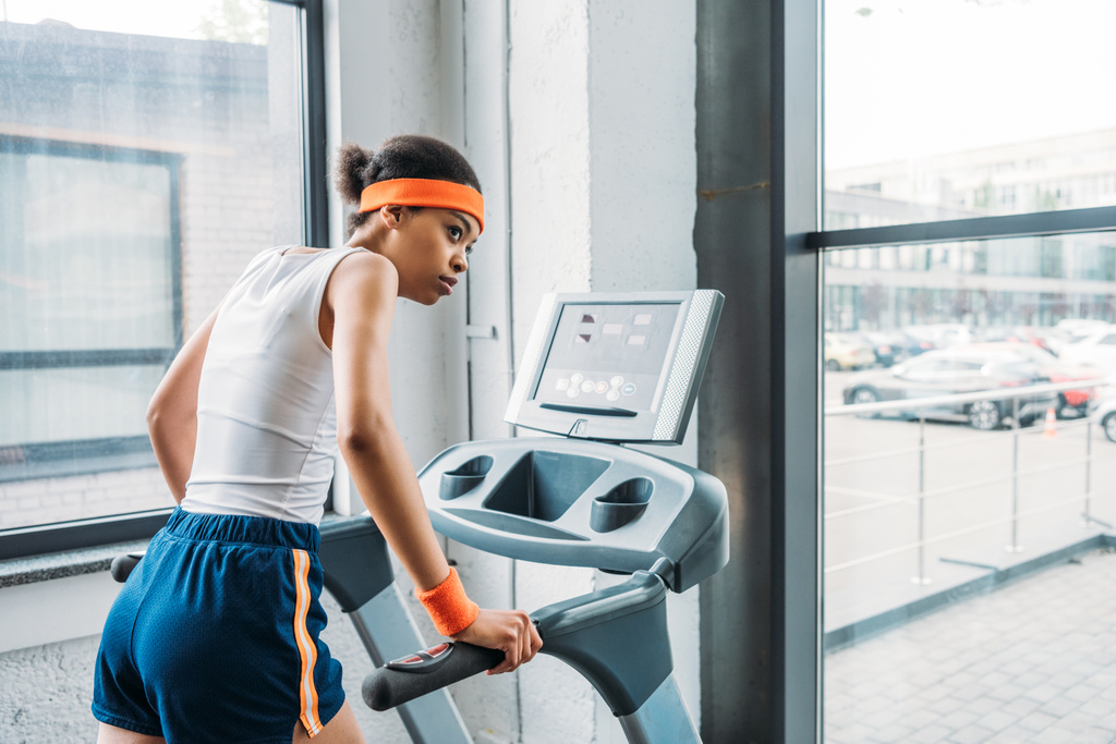 spor salonunda koşu bandı üzerinde çalışan genç Afro-Amerikan kadın jogging yapan  - Fotoğraf, Görsel