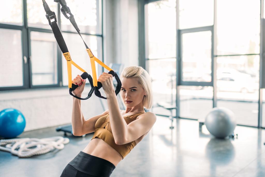 portrait of young caucasian sportswoman training with resistance bands at gym - Photo, Image