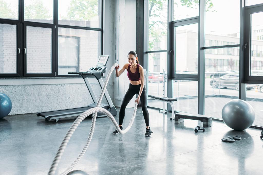 asian sportswoman working out with battle ropes at gym - Photo, Image