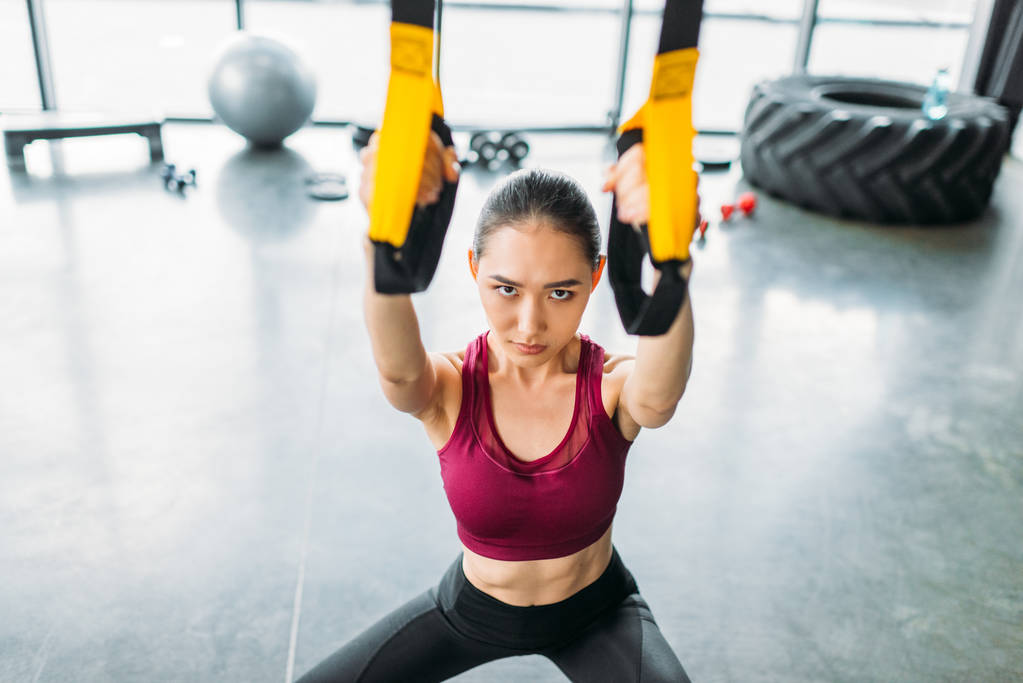 alto ángulo vista de asiático mujer atleta entrenamiento con resistencia bandas en gimnasio
 - Foto, Imagen