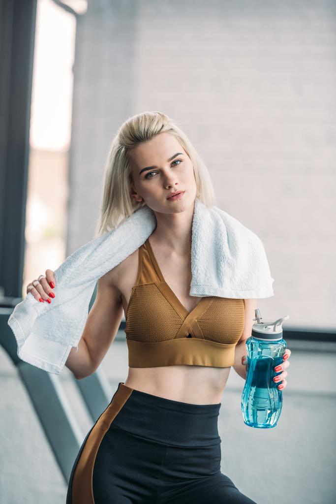 Porträt einer jungen Sportlerin mit sportlicher Wasserflasche und Handtuch nach dem Training im Fitnessstudio - Foto, Bild