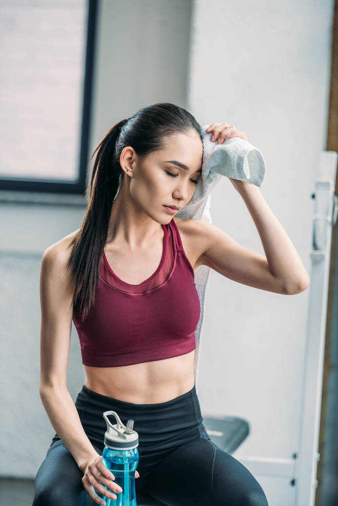 zmęczony sportsmenka Azjatka z ręcznikiem i butelka wody po treningu w siłowni - Zdjęcie, obraz