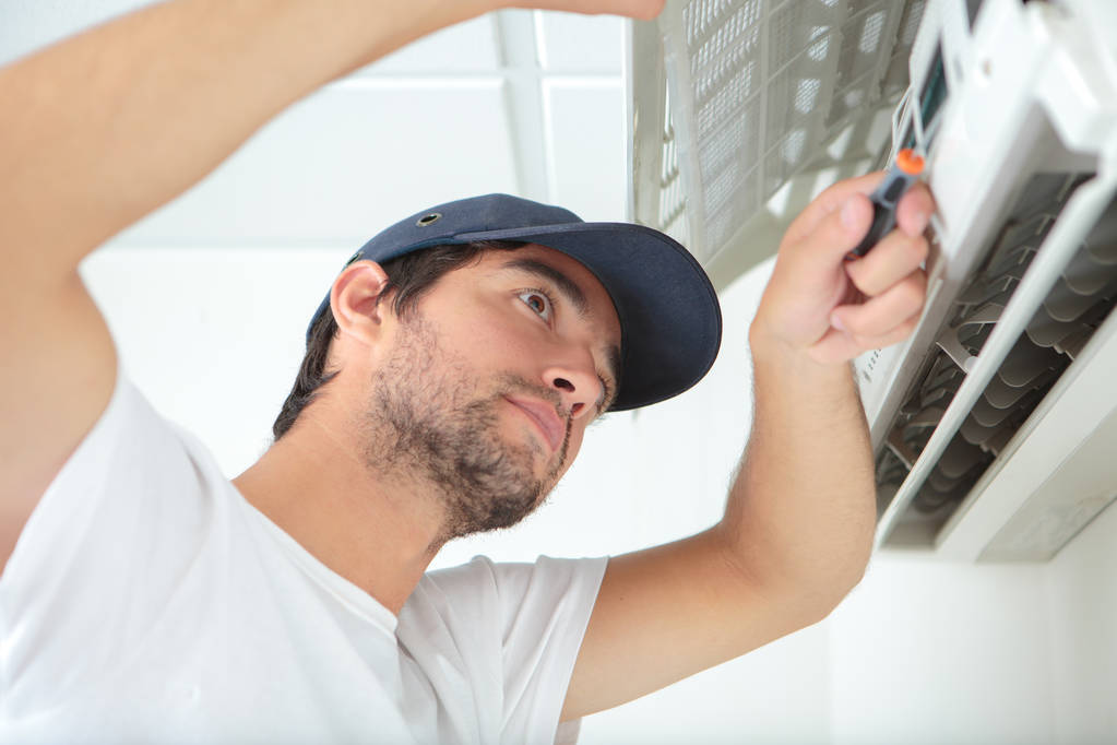 Mies korjaamassa ilmastointilaitetta
 - Valokuva, kuva