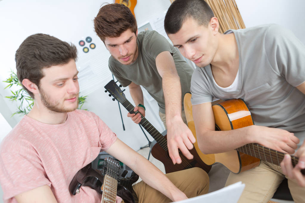 homens jovens tocando guitarra no quarto brilhante
 - Foto, Imagem