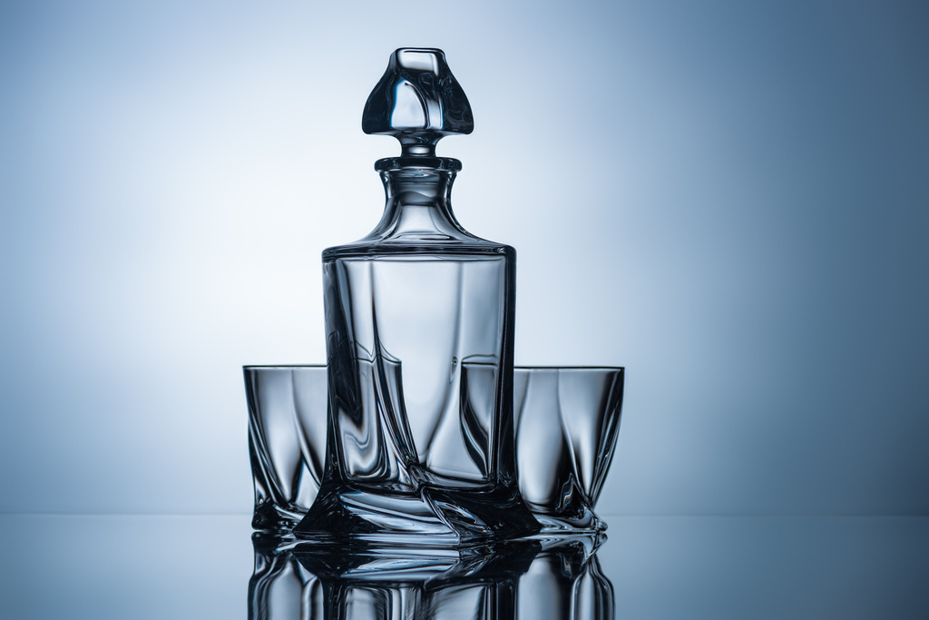 bicchieri di whisky e bottiglia vuota su grigio con riflesso
 - Foto, immagini