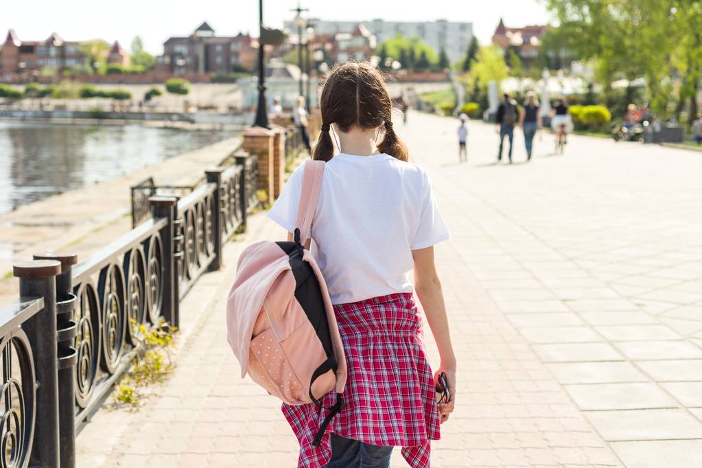 Κορίτσι εφηβική φοιτητής περπάτημα στο δρόμο με το σακίδιο. Πίσω στο σχολείο, πίσω όψη. - Φωτογραφία, εικόνα