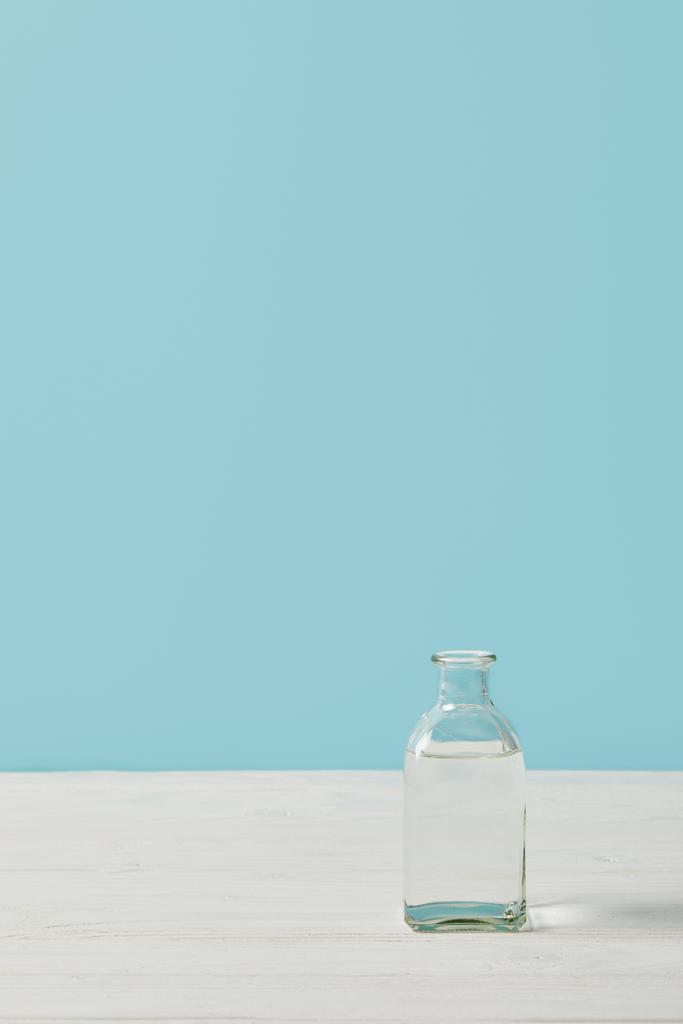 bouteille d'eau en verre sur plateau blanc isolé sur bleu
 - Photo, image