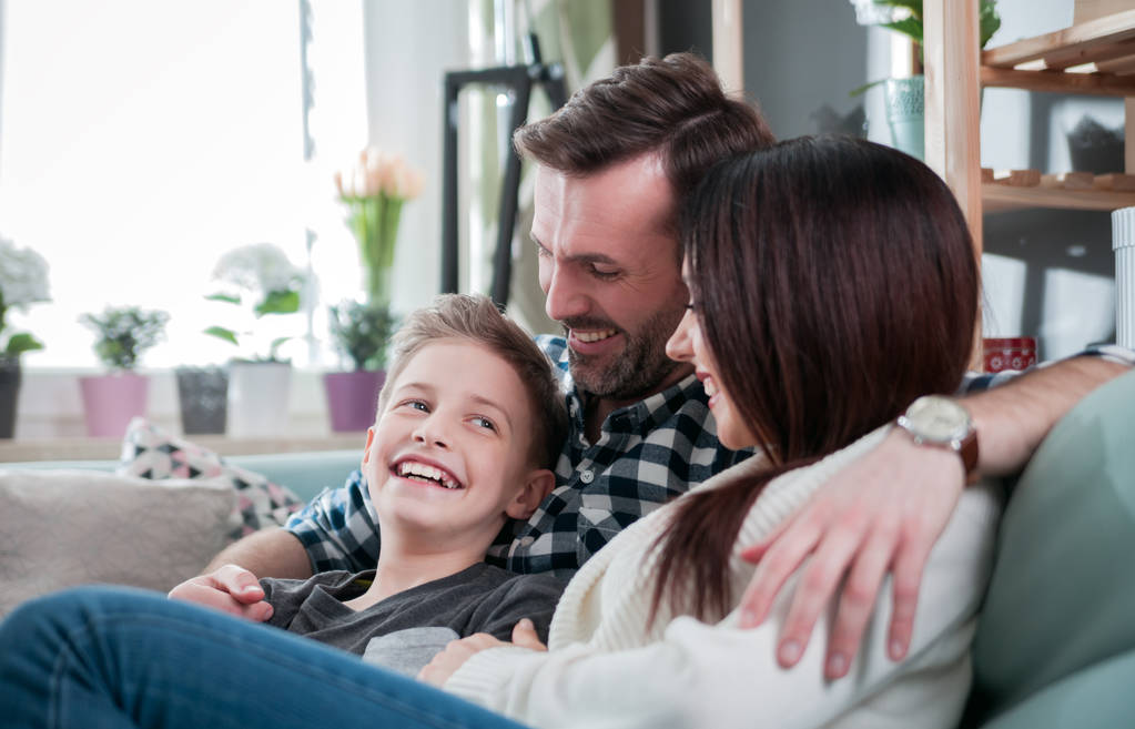 Młody szczęśliwy kochającą rodzinę, siedząc na kanapie w domu - Zdjęcie, obraz