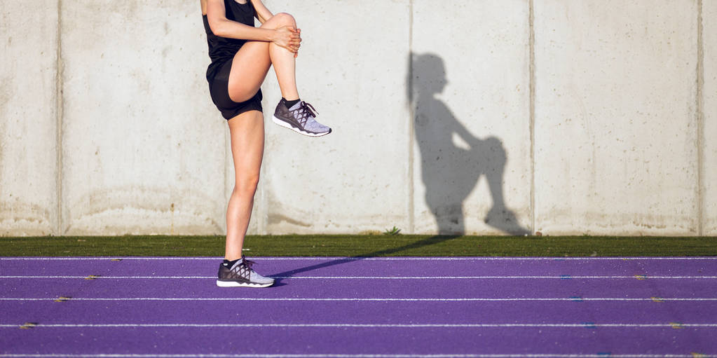 joven atlética mujer estirándose en pista de atletismo del estadio antes de correr
  - Foto, imagen