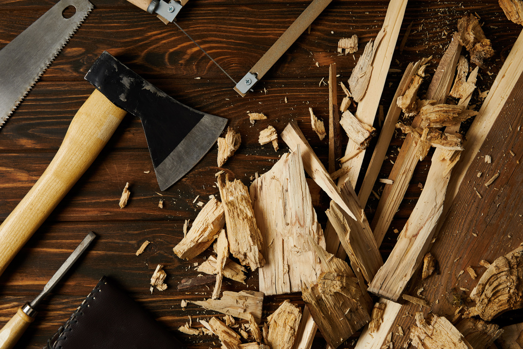 сокира, стамеска, ножівка та дерев'яні шматочки на коричневій стільниці
  - Фото, зображення