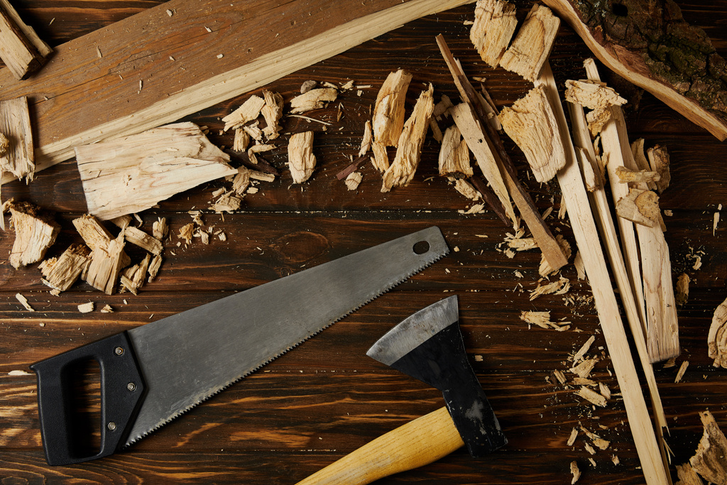 vista elevada de hacha, sierra de mano y piezas de madera sobre mesa marrón
 - Foto, imagen