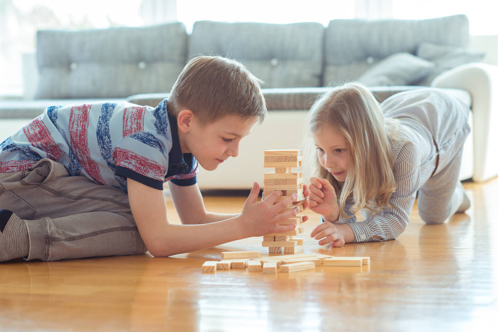 Due fratelli felici che giocano un gioco con blocchi di legno a casa con gioia
  - Foto, immagini