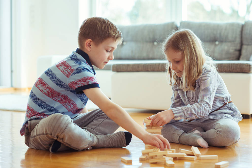 Dva šťastní sourozenci hrát hru s dřevěnými bloky doma radostně  - Fotografie, Obrázek