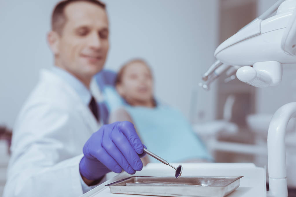 Αρσενικό οδοντίατρος λαμβάνοντας στοματικός καθρέφτης - Φωτογραφία, εικόνα