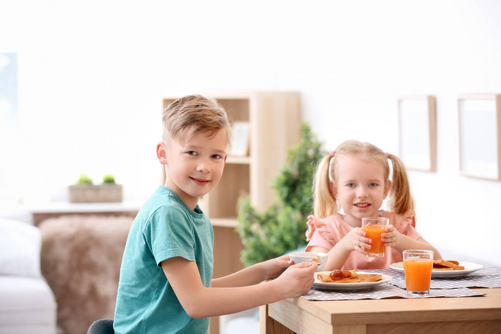 Adorable little children eating tasty toasted bread with jam at table - Photo, Image