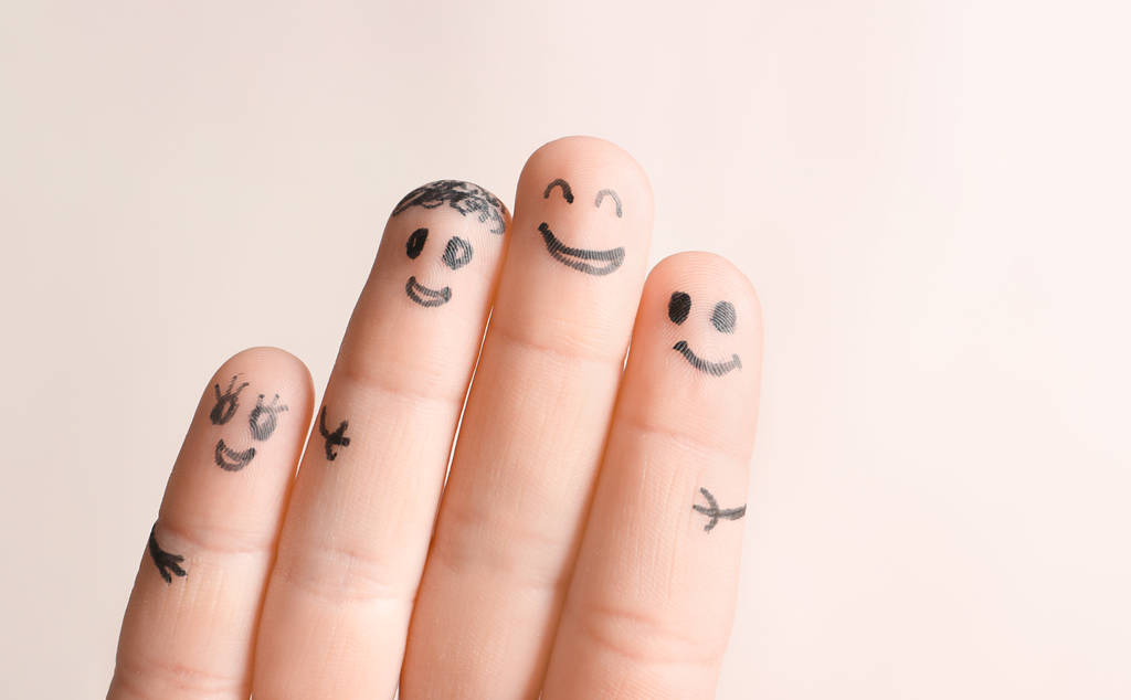 Τα δάχτυλα με τα σχέδια της χαρούμενα πρόσωπα ενάντια σε ανοιχτόχρωμο φόντο. Έννοια της ενότητας - Φωτογραφία, εικόνα
