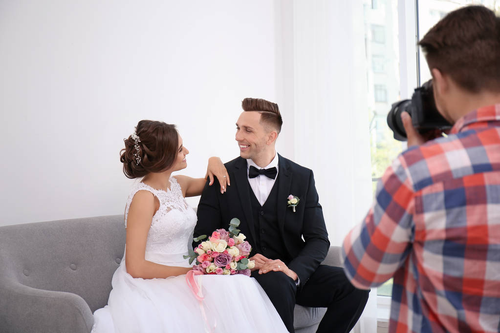 Профессиональный фотограф фотографирует свадебную пару в студии
 - Фото, изображение