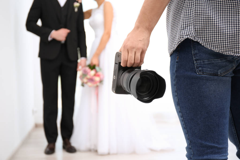 Fotógrafo profesional con cámara fotográfica y pareja de boda en estudio
 - Foto, Imagen
