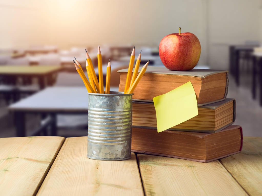 Πίσω στο σχολείο έννοια με μολύβια, μήλο και παλιά βιβλία σε ξύλινο τραπέζι πέρα από το εσωτερικό υπόβαθρο classrooom - Φωτογραφία, εικόνα