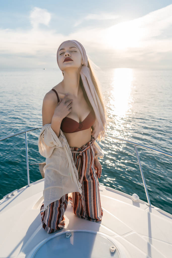 роскошная молодая женщина в стильной одежде наслаждается богатой жизнью и теплом на яхте
 - Фото, изображение