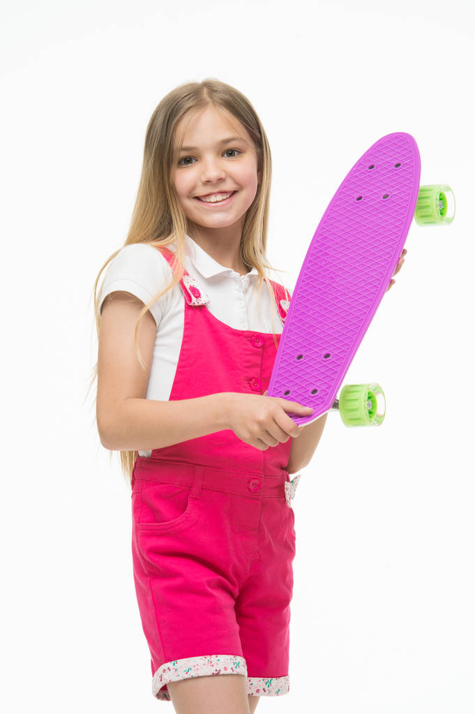 Skateboard kid in pink jumpsuit. Small girl smile with skate board isolated on white. Child skater smiling with longboard. Sport activity and energy. Childhood and active games. Just relaxing - Photo, Image