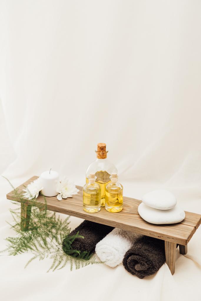 zblízka pohled na uspořádání lázeňské léčby příslušenství s kapradiny, ručníky, ropa a oblázky na bílém pozadí - Fotografie, Obrázek